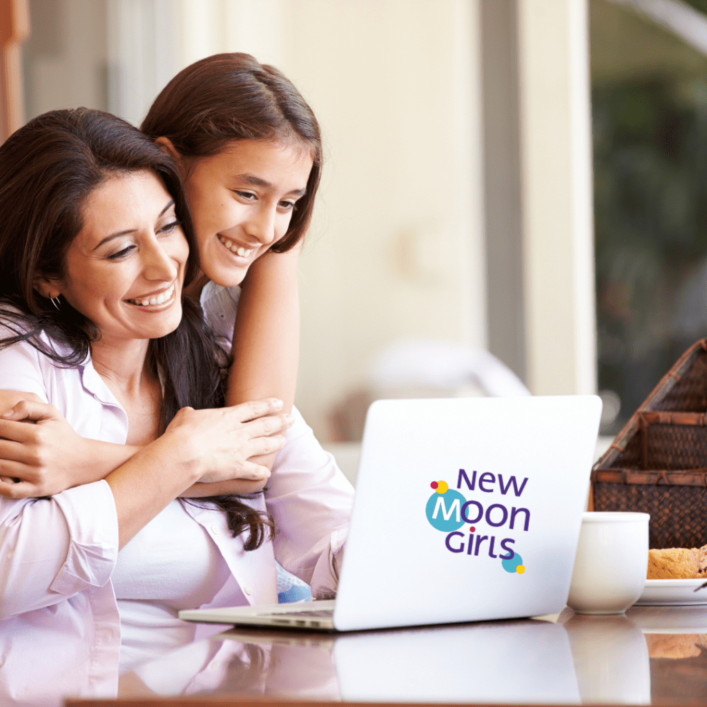 Mother and daughter looking at a laptop computer with New Moon Girls logo on the back.