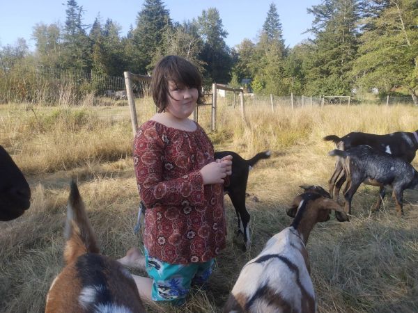 10 year old White girl in field with several goats
